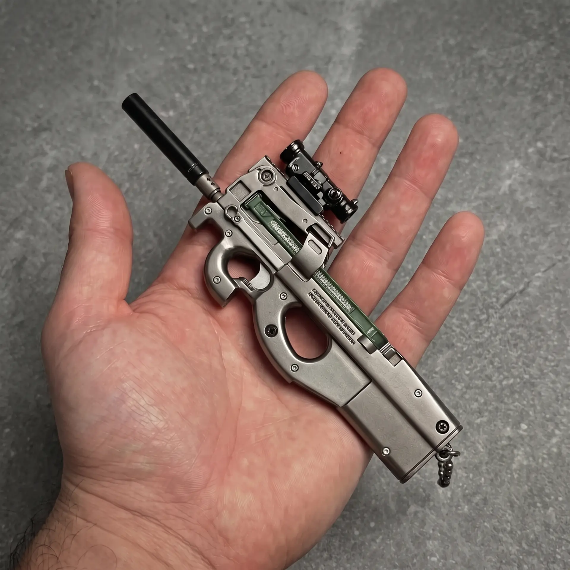 GRIMWERK P90 metal keychain replica held in a palm